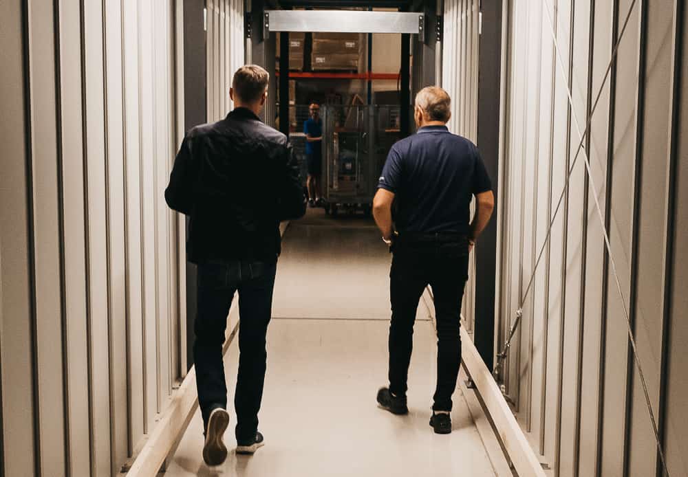 GS-Bildeler Mitbegründer Trond Gule und Element Logic Sales Manager Øyvind Kollerud, gehen durch den maßgeschneiderten Tunnel durch das AutoStore-System im Oslo-Lager.